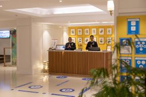 穆索里Fortune Resort Grace, Mussoorie - Member ITC's Hotel Group的两个坐在大厅柜台的男人
