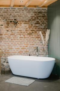 西内La cabane du potager - Ferme de Linciaux的砖墙客房内的白色浴缸