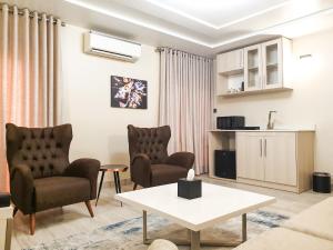 阿布贾Musada Luxury Hotels and Suites的客厅配有两把椅子和一张桌子
