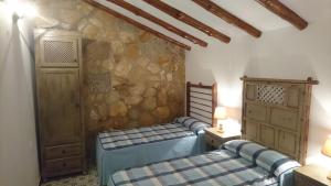 托雷斯Casas Rurales Cortijos el Encinar的一间卧室设有两张床和石墙