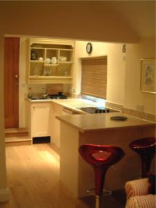 佩恩斯威克Tibbiwell Lodge的一间厨房,配有白色橱柜和一个带酒吧凳的岛屿