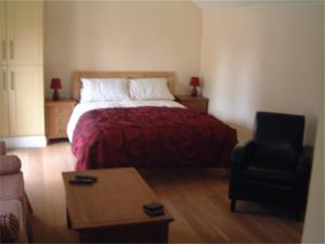 佩恩斯威克Tibbiwell Lodge的一间卧室配有一张带红色毯子和椅子的床