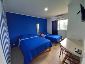 LomaHotel Grosseto Palma Real的一间蓝色卧室,配有两张床和一张书桌