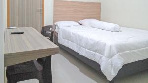 KaremaRedDoorz Syariah at Karema Area Mamuju的一间卧室配有一张床和一张木桌