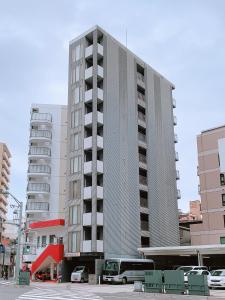 广岛OUCHI HOTEL Fujimi的一座高大的建筑,前面有一辆公共汽车停靠