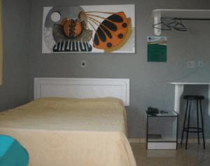 帕尔马斯Hotel Graciosa Palace的卧室配有一张床,墙上挂着蝴蝶的照片