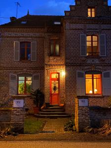 CahonLe Jardin, chambres d'hôtes en Baie de Somme的夜间有红门的砖房