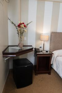 圣米格尔·德·图库玛Hotel Embajador的卧室配有一张桌子,上面有花瓶