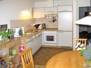 朱列斯拉赫Apartment Juliusruh-2 by Interhome的厨房配有白色橱柜和木桌