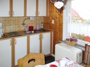 GarzHoliday Home Kaiser by Interhome的厨房配有白色橱柜、水槽和桌子