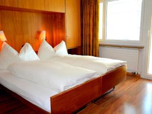 圣莫里茨欧瓦考茨纳12/14公寓的一张配有白色床单和木制床头板的大床