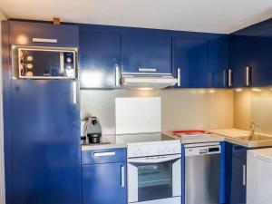 朋泰雷克Holiday Home Les Jardins de l'Océan-38 by Interhome的厨房配有蓝色橱柜和白色炉灶烤箱。