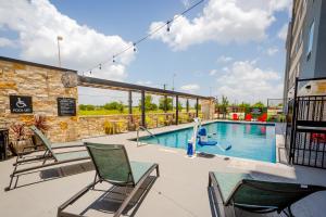 普弗拉热维尔Tru by Hilton Pflugerville, TX的一座带椅子的游泳池以及一座建筑