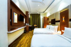 阿姆利则Hotel Aura Grand By Levelup Hotels的酒店客房设有两张床和电视。