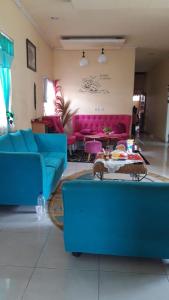 鲁滕D-Rima Homestay Ruteng的客厅配有蓝色的沙发和粉色家具