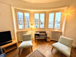 南特Appartement de Charme de 75m², Lumineux et Calme的客厅配有2把椅子和平面电视