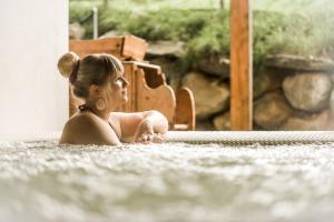 布鲁尼科阿玛腾酒店的坐在热水浴缸中的年轻女人