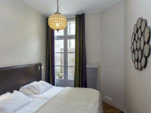 波尔多切维鲁博尔德公寓的一间卧室设有一张床、一个窗户和一个吊灯。