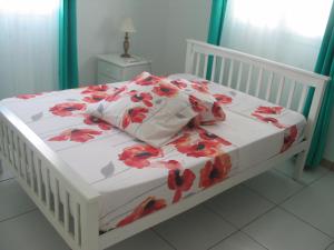 Quartier Morne la ValeurPETIT PARADIS的一张白色的床,上面有红花毯