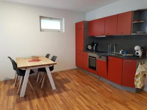 盖尔绍Studio am Dorfplatz的厨房配有红色橱柜和桌椅