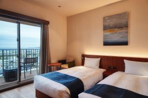 宜野湾市THE GRAND HOTEL GINOWAN的酒店客房设有两张床和一个阳台。