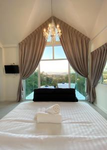 清莱La Maison Blanche Chiang Rai Resort的一间卧室配有一张带吊灯和窗户的床。