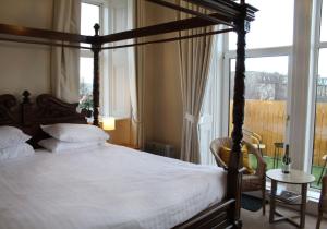 拉格斯伍德豪斯酒店的一间卧室设有天蓬床和窗户。