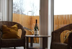 拉格斯伍德豪斯酒店的两把椅子旁的桌子上放一瓶葡萄酒