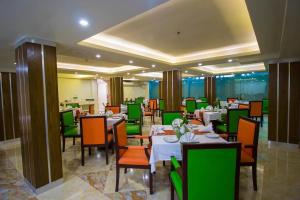 达卡Hotel Gulshan Lake View的一间在房间内配有桌椅的餐厅