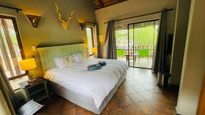 侯斯普瑞特Ujabule Lodge的一间卧室配有一张带白色床罩的大床
