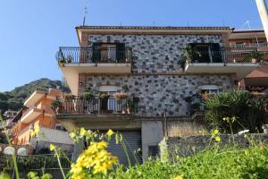陶尔米纳La Perla的一座砖砌建筑,设有阳台,种植了植物