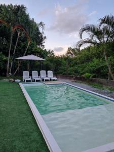蜜岛Bossa Beach House的一个带两把椅子和遮阳伞的游泳池