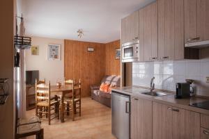 毕斯卡斯El Rincón de Andrea Apartamentos的厨房配有木制橱柜、桌子和沙发。
