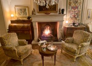 圣利斯Château Ratou的客厅设有壁炉、2把椅子和1张桌子