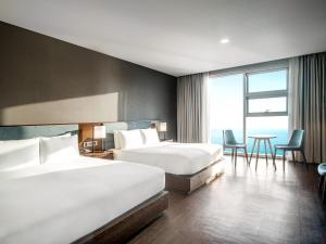 江陵市拓扑斯10号酒店的酒店客房带两张床和一张桌子以及椅子。