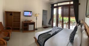 乌布Pondok Serayu的一间卧室设有一张床、一台电视和一个阳台。