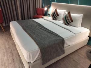 纳威孟买瑜珈大都会酒店的卧室配有一张带白色床单和枕头的大床。