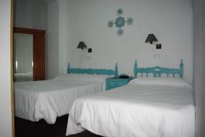 兰哈龙Hotel Lanjaron的卧室内的两张床,配有白色床单