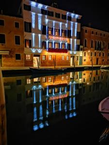 威尼斯Ca' Bonfadini Historic Experience的一座建筑物,晚上有灯光反射在水中