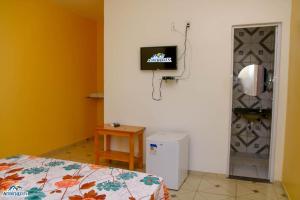 日若卡-迪热里科阿科阿拉Pousada aconcheg'us的一间房间,配有一张床和墙上的电视
