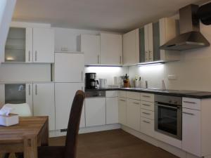罗尔多夫Ferienwohnung Staudacher的厨房配有白色橱柜和木桌