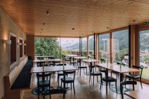 希洛谢克Naturhotel Chesa Valisa的餐厅设有桌椅和大窗户。