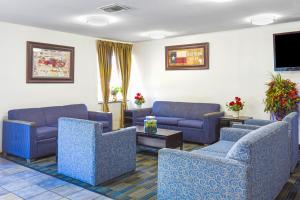 欧文OYO Hotel Irving DFW Airport South的一间设有蓝色沙发和平面电视的等候室