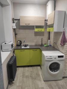 克里沃罗格New apartments Уютная студия в центре города Дзержинка的厨房配有绿色橱柜和洗衣机。
