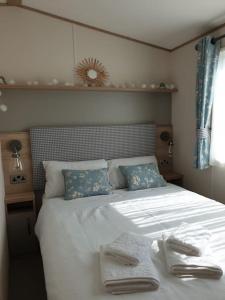 坎伯利The Sea Breeze - 8 Berth Premium Caravan in Camber Sands的一间卧室配有一张床,上面有两条毛巾