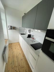克莱蒙费朗Hyper centre : Appart ancien rénové / tout confort的厨房铺有木地板,配有白色橱柜。