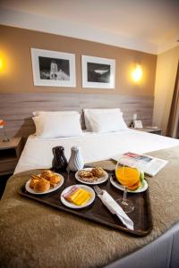 特雷索波利斯城际特雷索波利斯酒店的床上装有食物和饮料的托盘