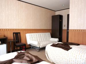 中富良野町布兰内宜吉佩提酒店的酒店客房带两张床和一张白色沙发