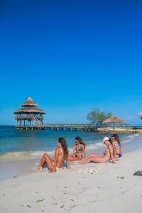 Tintipan IslandEl Embrujo Tintipan的坐在海滩上的四个比基尼女人