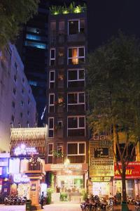 胡志明市CHERRY BOUTIQUE HOTEL的一座高大的建筑,晚上在城市里设有商店
